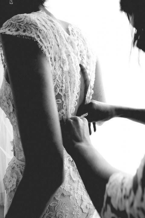Hands fastening the back of a bride's wedding dress